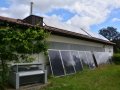 Gräfendorf – venkovní jednotka tepelného čerpadla vzduch – voda a teplovodní solární kolektory na střeše blízké hospodářské budovy
