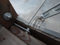 Detail prostupu ocelového táhla krovu oplechováním římsy. Dřevěný nosný sloupek zapuštěný do oplechování.